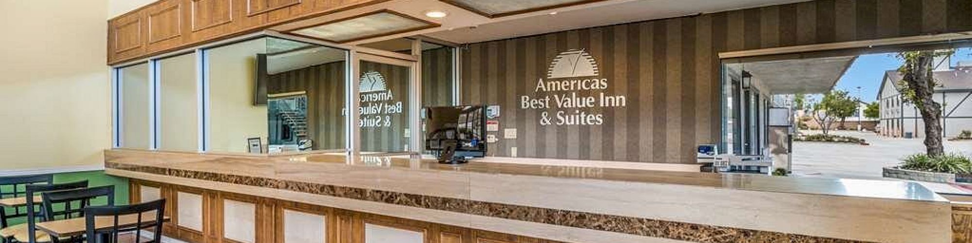 A hotel reception area with a wooden front desk and chairs, labeled 