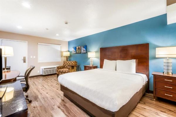 A hotel room with a large bed, two bedside tables, a sitting area, and a desk. The walls are painted blue and beige.