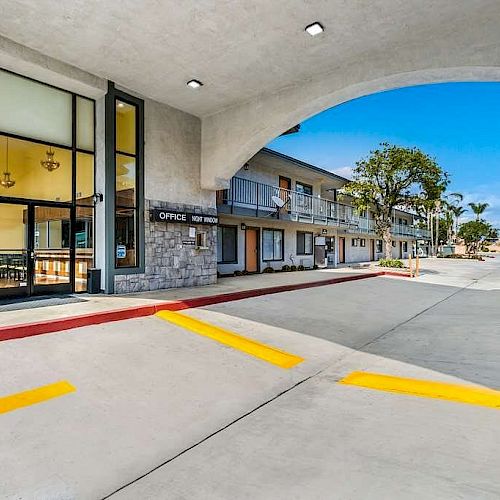 The image shows the entrance of a hotel or motel with a covered driveway, signage for the main entrance, and an arrow directing traffic flow.