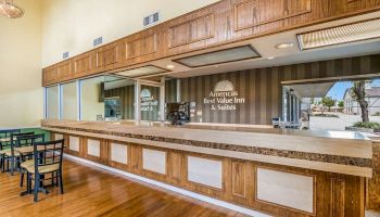 The image shows the reception area of America's Best Value Inn & Suites, with a long wooden counter and seating area adjacent.